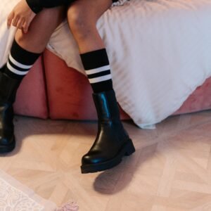 Fashionable black leather boots paired with trendy striped socks for a chic look.